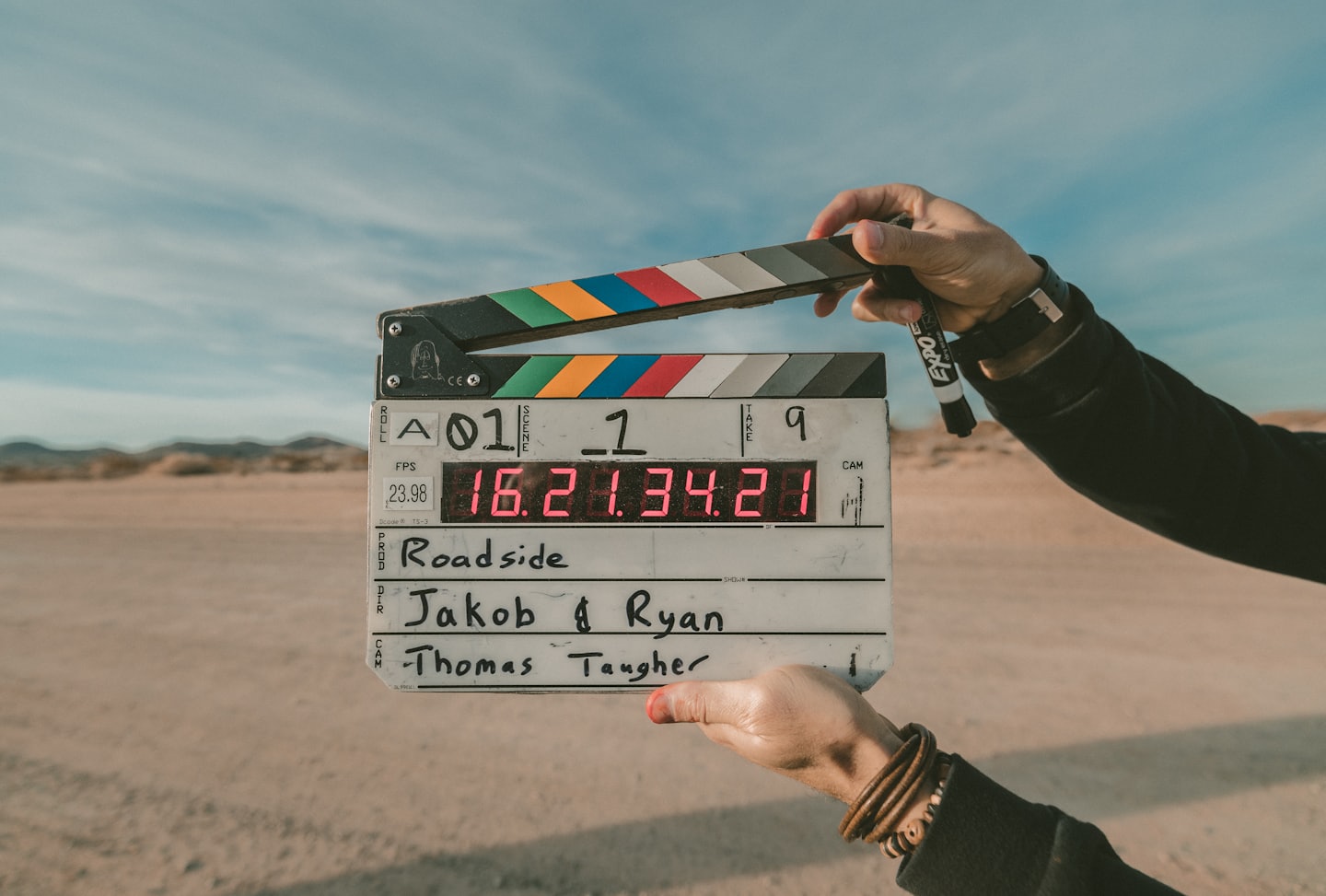 A film slate raised against a desert sky on an independent film set