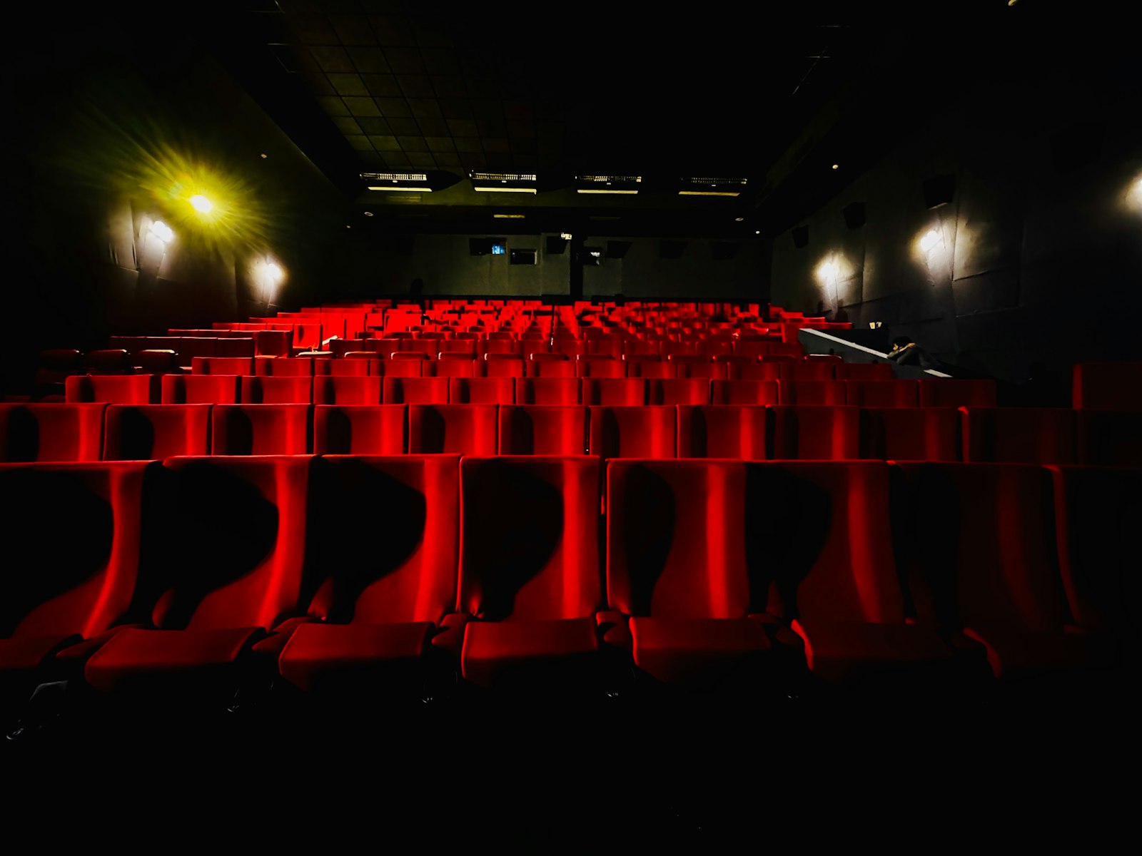 Rows of red cinema seats in a darkened auditorium
