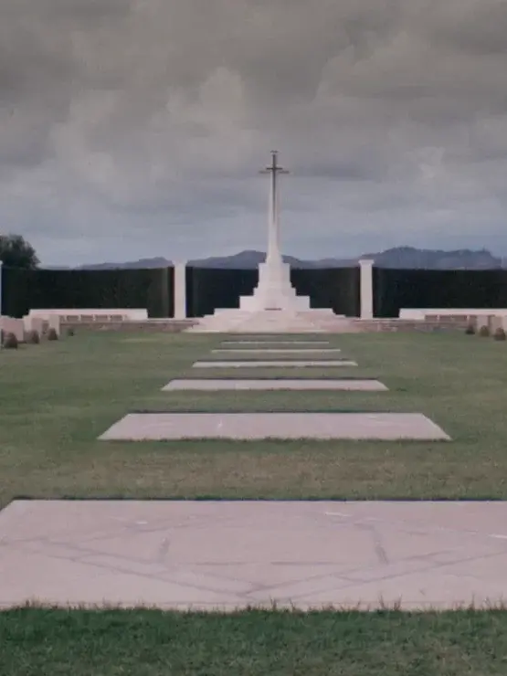 War memorial cemetery in Sicily, with a stone cross overlooking rows of flat headstones, evoking the memory at the heart of Lost Love